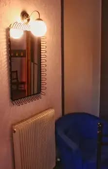 Specchio sopra al termosifone della camera da letto, con a lato una poltrona blu